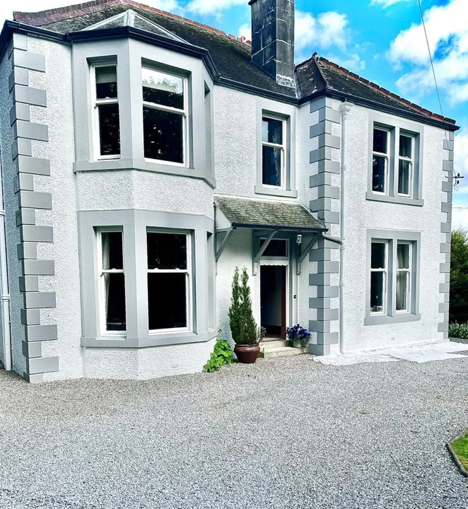 Detached stone villa freshly painted white with grey quoins and window surrounds