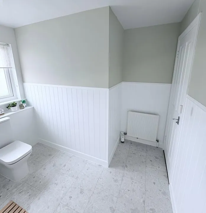 Bathroom with sage green walls above white painted tongue-and-groove panelling