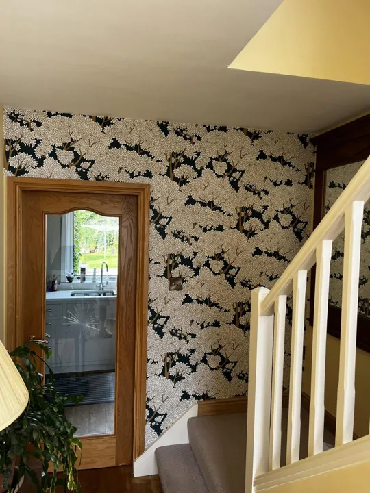 Hallway feature wall hung with tree-pattern wallpaper beside the staircase