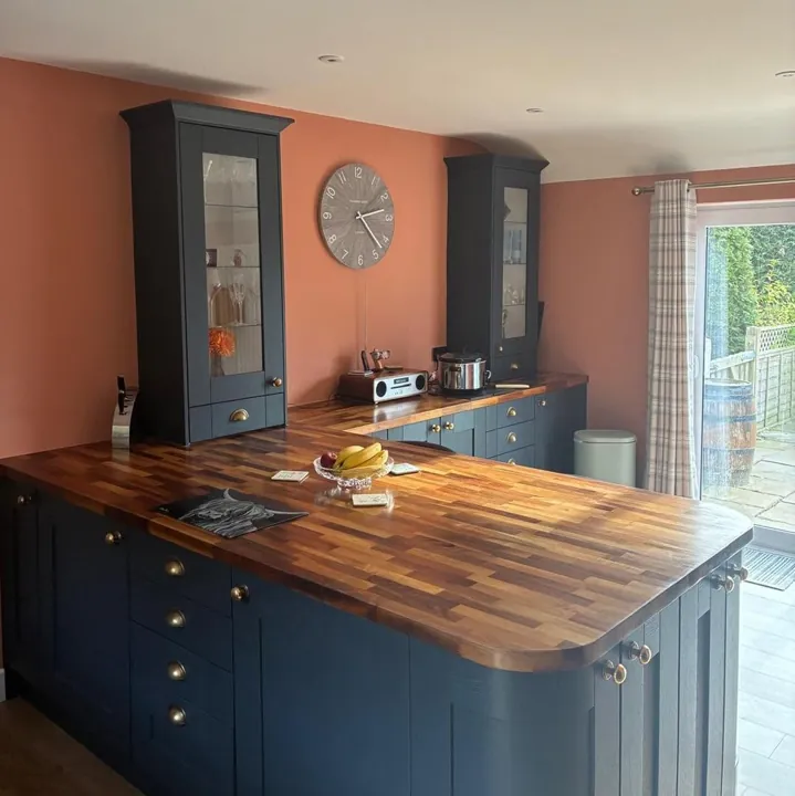 Kitchen decorated with warm terracotta painted walls and white ceiling, navy cabinets and worktops in place