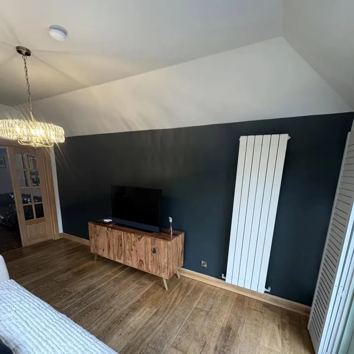 Living room with a deep teal painted feature wall and crisp white ceiling