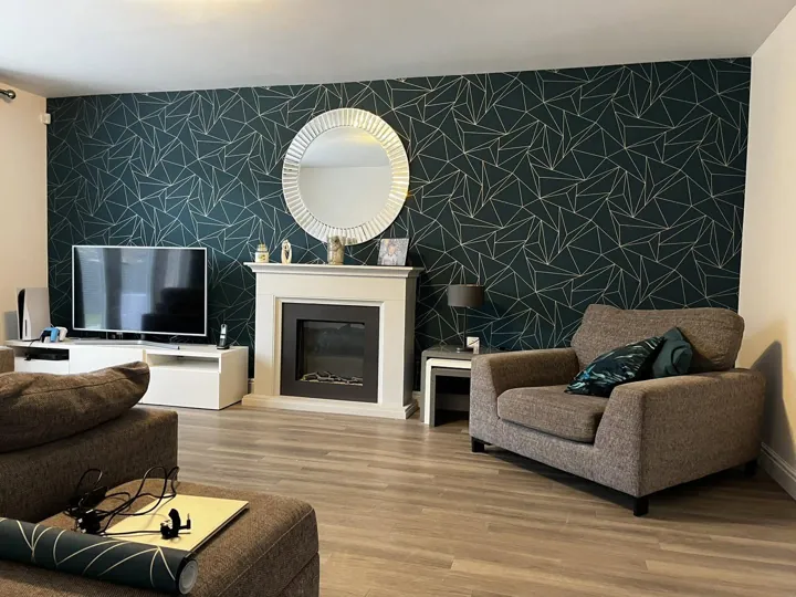 Living room with a dark teal geometric feature wallpaper behind a white fireplace, Dumfries & Galloway